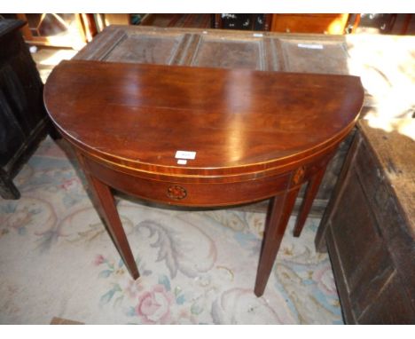 A George III mahogany card table, the demi-lune foldover top supported by a single gate on square tapering supports, 91cm wid