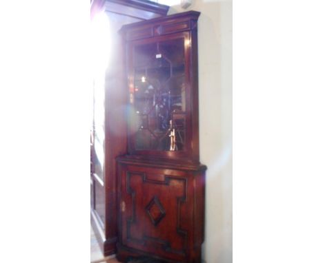 A reproduction oak floor stranding corner cupboard, having moulded cornice over astragal glazed door, enclosing three shaped 