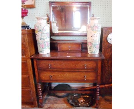 A 1920's oak dressing chest, having adjustable mirror over trinket drawer and two further long drawers on bobbin turned and b