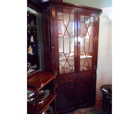 An early 19th century oak floor standing corner cupboard, the moulded cornice above a pair of astragal glazed doors enclosing