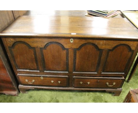 AN ANTIQUE OAK MULE CHEST, THE HINGED LID ABOVE A FOUR ARCHED PANEL FRONT WITH TWO SHORT DRAWERS BELOW, RAISED ON SHAPED BRAC