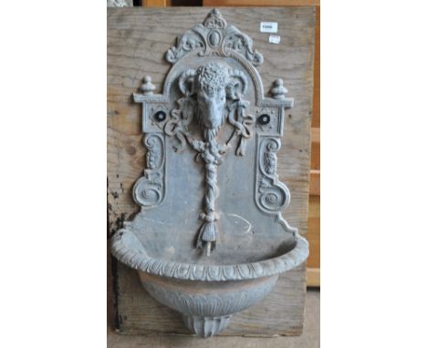 A 20th century lead wall mounted fountain centred with a ram's head decorated with swags and garlands above a gadrooned basin