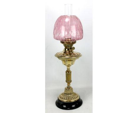 A brass oil lamp with duplex burner, cranberry shade and clear glass chimney on circular base, height including chimney appro