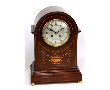 An Edwardian mahogany and inlaid mantel clock with domed top and circular dial set with Arabic numerals, on plinth base with 