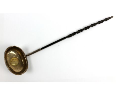 A George III white metal and wrythen baleen handled toddy ladle, the plain oval bowl with flared rim set with&nbsp;an 1812 1s