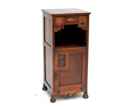 An oak bed side table with compartmentalised drawer above shelf and single door decorated with portrait of a Native American,