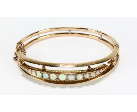 An Edwardian 9ct yellow gold snap bangle set with thirteen graduated opal cabochons, 6 x 5cm, hallmarked for Chester 1906, ap