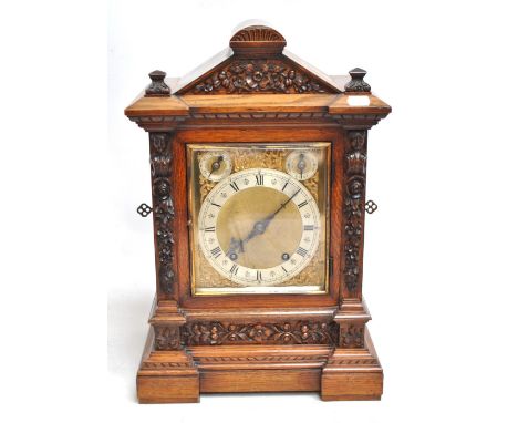 WINTERHALDER &amp; HOFMEIER; an oak cased mantel clock with carved foliate decoration, the silver chapter ring set with Roman