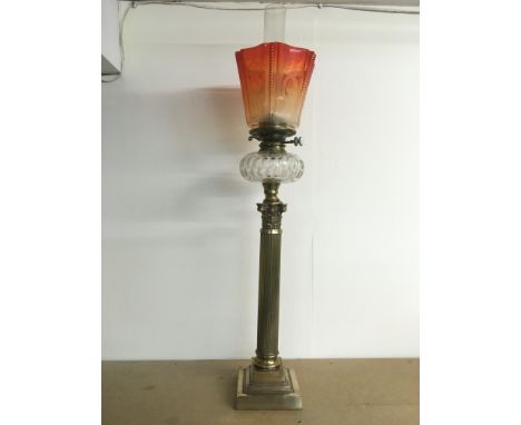 A large Corinthian column oil lamp with orange glass shade, approx height 90cm.