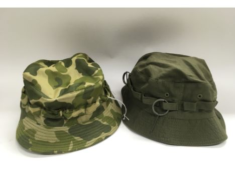 A Vietnam war era US army jungle boonie hat adorned with grenade rings plus another boonie hat made from parachute material.