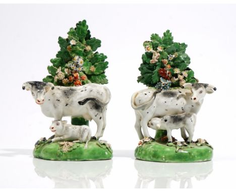 A pair of Derby porcelain cow and calf groups, early 19th, each before a flowering tree on a grassy mound base, unmarked, (a.