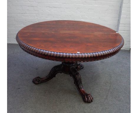 A late Regency rosewood centre table, the circular tilt-top with a gadrooned edge and bead and reel moulding, on  lotus carve