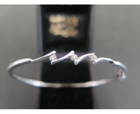 A diamond hinged bangle - Each of the three brilliant-cut diamonds in a crossover style tension setting to the plain bangle -