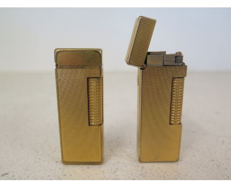 Two gilt metal Dunhill lighters with engine turned decoration 