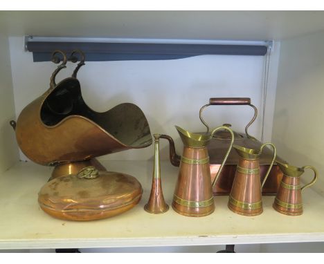 A copper range kettle, a copper helmet coal scuttle, three jugs, a horn and a warmer