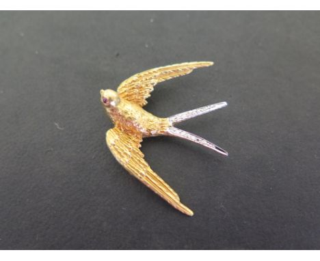 An 18ct gold diamond swallow brooch - The textured bird with ruby cabochon eyes and single-cut diamonds to the tail - Hallmar