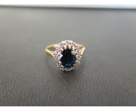 A sapphire and diamond cluster ring - The oval sapphire within a single-cut diamond surround - Stamped 18ct - Ring size Q - W
