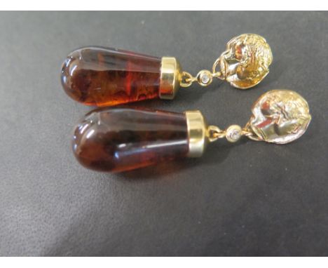 A pair of amber-like drop ear pendants - Each designed as the carved profile of a lady suspending a rose-cut diamond collet a