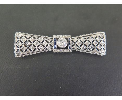 A diamond and sapphire bow tie brooch - The old-cut diamond collet and square-shape sapphire lines to the pierced detail set 