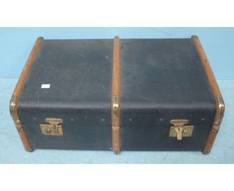 A large black suitcase/trunk bound with wood and brass, approx 77x 48cm