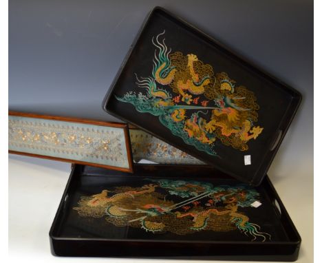 A pair of Oriental lacquered trays depicting the Dragon chasing the pearl; a pair of framed silk panels; an early 20th to mid