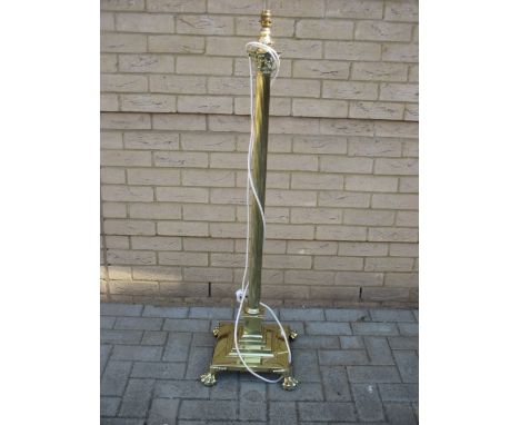 A brass standing lamp in the form of a Corinthian column, on a stepped base with four paw feet (128cm high not including shad
