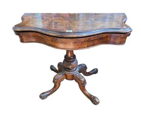 Victorian figured walnut fold top card table of serpentine form on carved pedestal to four scrolled legs.