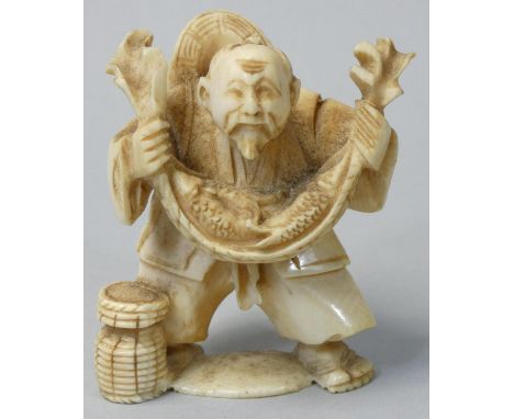 A Japanese Ivory Netsuke, carved as a fisherman with his catch, signed, height 5 cm. 