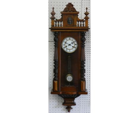 A Vienna style walnut wall clock, with two part white enamel dial with Roman numerals, to an architectural case with mask ped