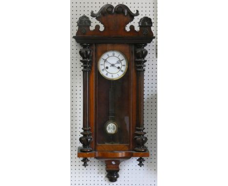 A Vienna style walnut wall clock, with two part white enamel dial with Roman numerals, to an architectural case, pendulum, 86