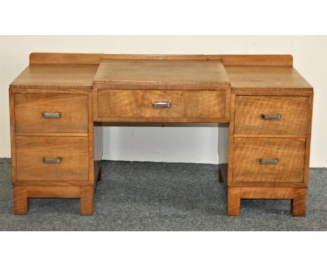 Heals; a child's light oak dressing table, button tab to right hand drawer, the stepped central drawer, flaked by two drawer 