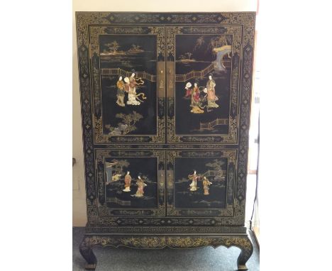 A Chinese black lacquer cabinet, the four doors and sides decorated with carved hardstone, ivory and mother of pearl figures,