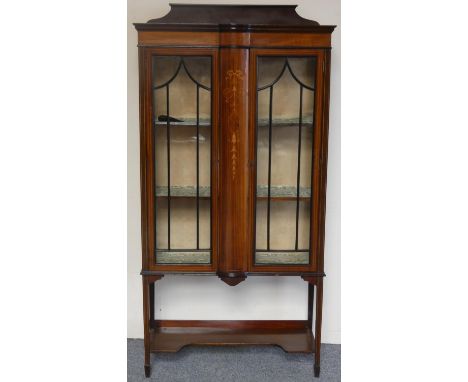 An Edwardian mahogany and boxwood inlaid display cabinet, the astragal glazed doors flanking a domed inlaid panel, tapering l