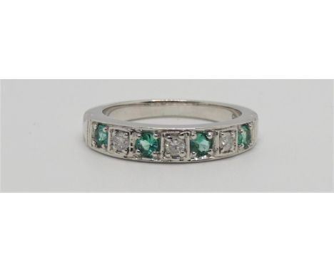 A 9ct white gold emerald and diamond half eternity ring, channel set with brilliant cut stones, size N. 