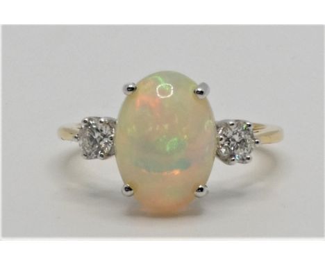 An 18ct gold opal and diamond three stone ring, claw set with a cabochon stone, measuring 13 x 8 mm, flanked by brilliant cut