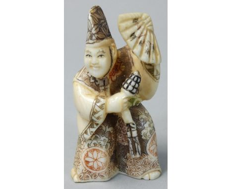 A Japanese Ivory Netsuke, carved and painted as a man with a fan, signed, height 6 cm. 