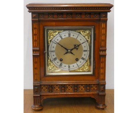 An Edwardian walnut and marquetry inlaid mantle clock, the gilt dial with silvered chapter ring, the Black Forest movement by
