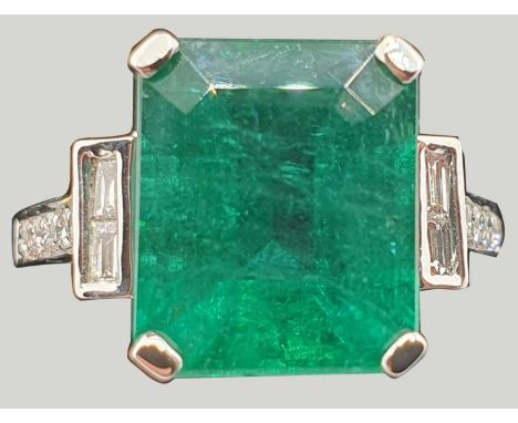 An 18 ct white gold emerald and diamond dress ring, claw set with a step cut stone, measuring 11.4 x 9.5 x 6.8 mm, calculated