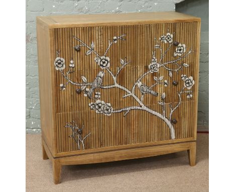 A reeded hardwood chest of three drawers decorated with a painted scene of perched birds and flowers.
