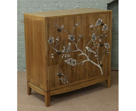 A reeded hardwood chest of three drawers decorated with a painted scene of perched birds and flowers.