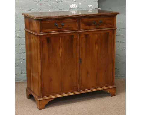 A yew wood two drawer side cabinet raised on bracket feet.