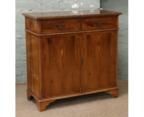 A yew wood two drawer side cabinet raised on bracket feet.