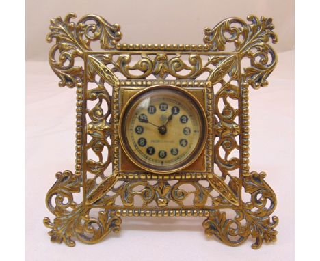 A brass easel clock, scroll pierced frame, the circular dial with Arabic numerals, 17.5 x 17.5cm