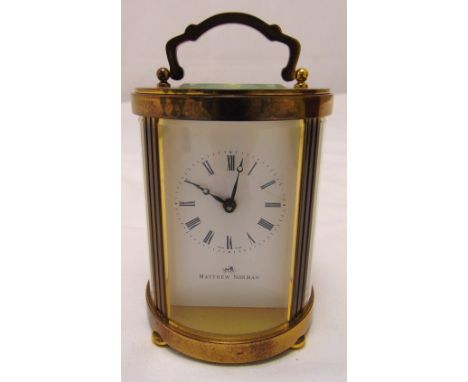 A Matthew Norman oval brass carriage clock with swing handle, white enamel dial with Roman Numerals, 11cm (h)