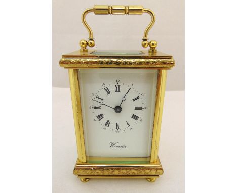 A brass carriage clock of customary form, white enamel dial with Roman numerals on four bun feet, to include key, 15 x 8 x 6.