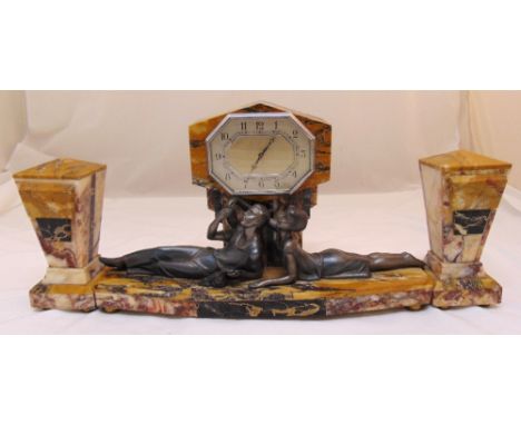 An Art Deco marble mantle clock set flanked by two garnitures and with cast figurines of a happy couple on shaped oval base, 