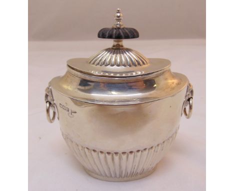 A hallmarked silver shaped oval tea caddy part fluted with lion mask ring handles pull off cover with ebonised wooden finial,