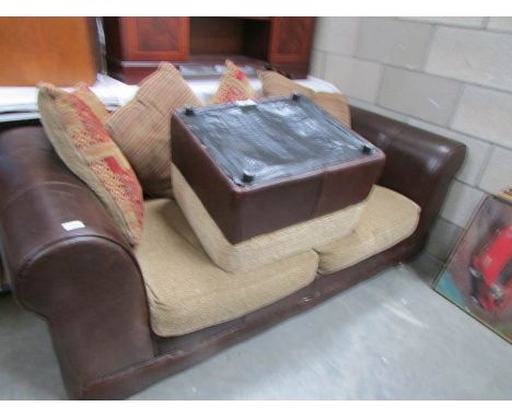 A leather sofa, pouffe and cushions