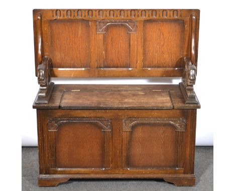 An oak monk's bench, 20th Century, hinged carved panelled back on lion supports, hinged box seat, above two panels, bracket f