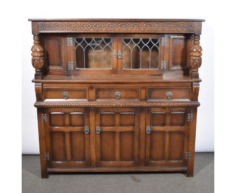 A reproduction oak dining suite comprising a court cupboard, the upper section with leaded glass doors, the base with drawers